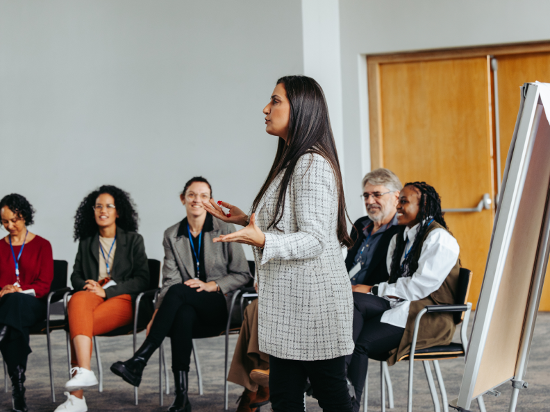 Woman presenting to a group in meeting.
