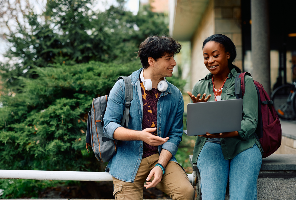 Two students discussing while looking at laptop.