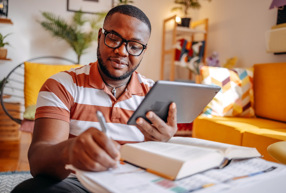 Man studying with tablet and notes.